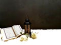 The lantern of Ramadan is black in color, luminous, decorated with wooden motifs, next to the Holy Quran