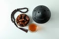 Lantern, rosary, glass of tea and bowl of dates on white background