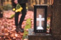 Lantern at tombstone. Defocused mourning woman holding flowers in hands and standing at grave Royalty Free Stock Photo