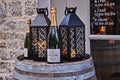 Lanterns with candles and bottles of champagne on wooden barrel for decoration at entrance to restaurant during