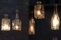 Lanterns made of glass bottles and Edison lamp bulbs. DIY lamps made from recycled old bottles hanging in cafe window. Royalty Free Stock Photo