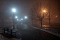 Lanterns trees and benches in the fog at night in the park. Late autumn night in the park. Wood benches and park alley Royalty Free Stock Photo