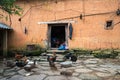 Lao Cai, Vietnam - Sep 7, 2017: Wall thick adobe style house closeup with Ethnic girl embroiders on door at her house with poultry