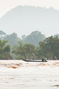 Laos fishermen on fishing boat in rapids of Mekong River. The Mekong River is going overflow. Tropical forest and mountains