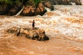 Laotian fisherman stands on the rapid on the Mekong River