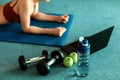 Laptop, apple, dumbbell and water bottle on the ground beside people