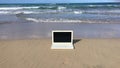 Laptop on the beach. Notebook on the sand near the ocean