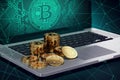 Laptop with Bitcoin symbol on-screen and piles of golden Bitcoin