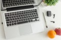 Laptop, black wireless earbuds, pen, potted plant, apple and orange isolated on white background
