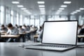 Laptop with blank mockup screen standing on desk during exam session at high school with students taking test on background Royalty Free Stock Photo