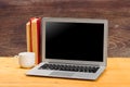 Laptop with blank screen, cup of coffee and books or notebooks on a wooden table. mockup for your text Royalty Free Stock Photo