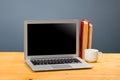 Laptop with blank screen, cup of coffee and books or notebooks on a wooden table. mockup for your text Royalty Free Stock Photo