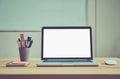 Laptop blank screen on the desk and writing equipment in the meeting room there is a white board on the back.