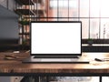 Laptop with blank screen mockup template on table in industrial old factory loft interior