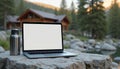 Laptop with blank screen on stone table. Mountain lodge backdrop. Notebook computer with water bottle. Concept workspace, Royalty Free Stock Photo