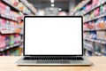 Laptop blank screen on wood table with supermarket in department store background, mockup, template for your text Royalty Free Stock Photo