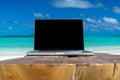 Laptop blank screen on wooden desk with beach. relax concept. Royalty Free Stock Photo