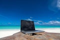 Laptop blank screen on wooden desk with beach. relax concept. Royalty Free Stock Photo