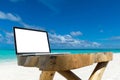 Laptop blank screen on wooden desk with beach. relax concept. Royalty Free Stock Photo