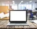 Laptop with blank screen on a wooden desk with blurred office and open book in background Royalty Free Stock Photo
