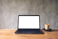 Laptop with blank white desktop screen and coffee cup on wooden table with brick wall background Royalty Free Stock Photo