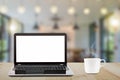 Laptop with blank white screen and hot coffee cup on vintage wooden table on blurred coffee shop background Royalty Free Stock Photo