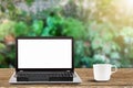 Laptop with blank white screen and hot coffee cup on vintage wooden table on blurred garden background Royalty Free Stock Photo