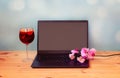 Laptop, branch of orchid and glass of sangria on wooden table