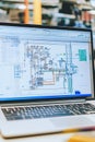 Laptop with CAD software open displaying a schematic of an electrical grid with wind and solar connections.