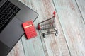 Laptop, calculator and shopping cart on wooden table. Online Shopping Concept