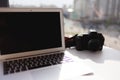 A laptop and a camera are on an office table in a bright room Royalty Free Stock Photo