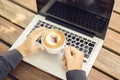 Laptop and cappuccino on a wooden table Royalty Free Stock Photo