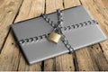 Laptop with chains and padlock on wooden