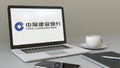 Laptop with China Construction Bank logo on the screen. Modern workplace conceptual editorial 3D rendering