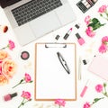 Laptop, clipboard, flowers, cosmetics and accessories on white background. Flat lay. Top view. Feminine freelancer composition