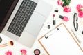 Laptop, clipboard, roses flowers, cosmetics and accessories on white background. Flat lay. Top view. Feminine freelancer compositi