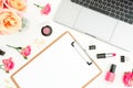 Laptop, clipboard, roses flowers and cosmetics on white background. Flat lay. Top view. Woman freelancer composition Royalty Free Stock Photo