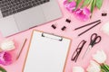 Laptop, clipboard, tulips flowers, glasses and accessories on pink background. Flat lay. Top view. Freelancer office concept