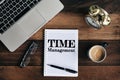 Laptop, clock, glasses, coffee and notebook with TIME MANAGEMENT word on a wooden table