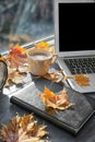 Laptop with coffee, book and autumn leaves on windowsill