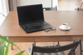 Laptop with coffee cup and glasses wooden table.