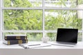 Laptop and coffee in indoor office. Blank laptop screen on a white desk and book and a cup of coffee, mock up. pencil and board. Royalty Free Stock Photo