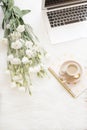 Laptop, coffee, notebook and a large bouquet white flowers on the floor on a white fur carpet. Freelance fashion comfortable femin Royalty Free Stock Photo