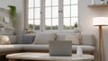 A laptop on a coffee table in a modern white and comfortable living room with a cosy couch