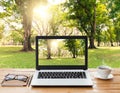 Laptop and coffee on wood workspace and park background Royalty Free Stock Photo