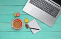 Laptop, colored macaroons cookies, cup of coffee, notebook with a pen on a blue wood table. Top view. Flat lay. Royalty Free Stock Photo