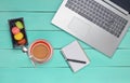 Laptop, colored macaroons cookies, cup of coffee, notebook with a pen on a blue wood table. Top view. Flat lay. Royalty Free Stock Photo
