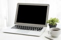 Laptop computer with black blank mockup screen on top of white office desk table with coffee cup and pen Royalty Free Stock Photo