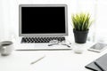 Laptop computer with blank mock up screen is on top of white office desk table with supplies Royalty Free Stock Photo