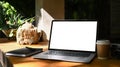 Laptop computer with blank screen, coffee cup and notebook on wooden table at outdoor. Royalty Free Stock Photo